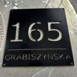 Zdjęcie przedstawia tabliczkę z numerem domu